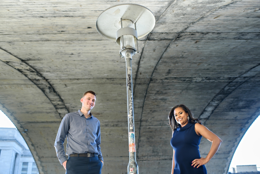 An engaged couple stand under the 30th street bridge in Philadelphia.